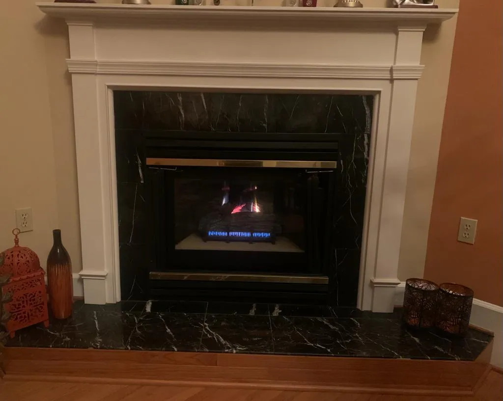 Cozy gas fireplace with a marble surround and decorative items nearby.