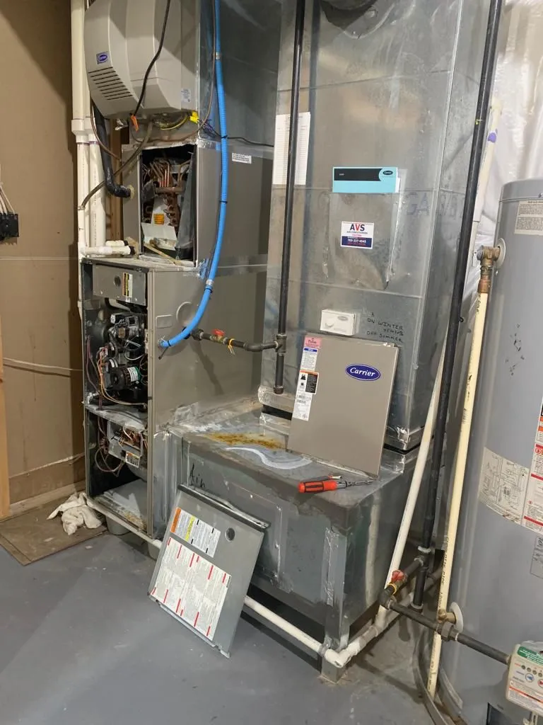 Understanding the Key Differences: Local HVAC Contractors vs. Larger Companies in Fairfax 1 HVAC system with a furnace, pipes, and water heater in a basement setting.